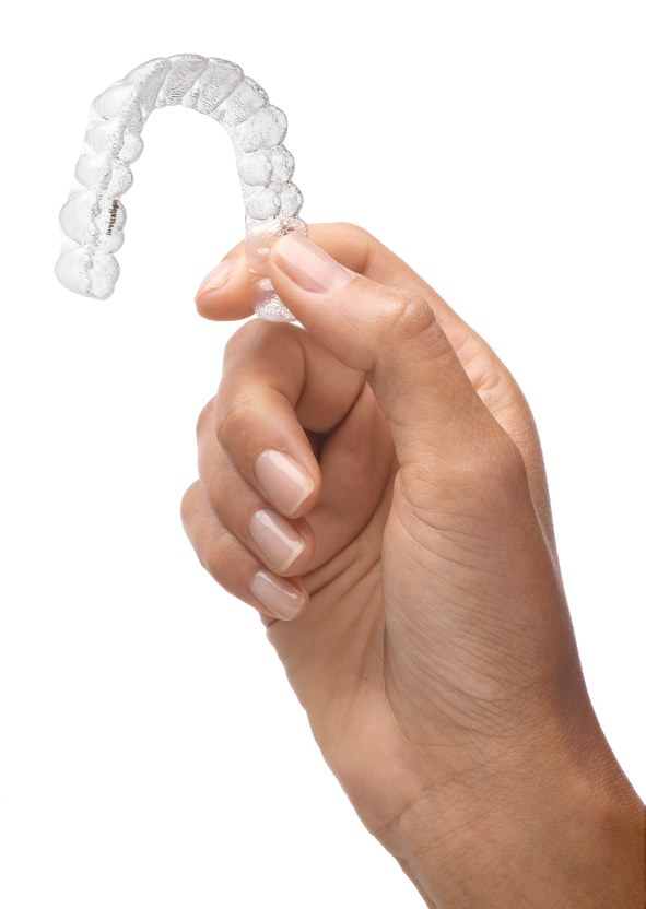 A clear Invisalign aligner held in the hand, showing that it is removable